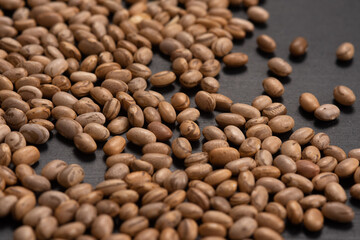 Carioquinha type beans over black background. Brazilian beans. Top view