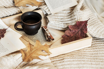Autumn, fall leaves, a hot steaming cup of coffee and a warm sweater on a wooden tray. Seasonal,...