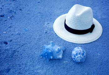 Pop art surreal style white straw hat on azure blue sand beach and seashells