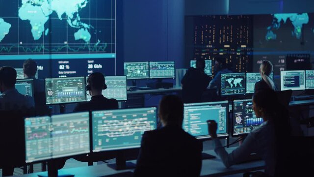 Team of Professional Computer Data Science Engineers Work on Desktops with Screens Showing Charts, Graphs, Infographics, Technical Neural Network Data and Statistics. Dark Control and Monitoring Room.