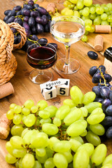  Traditional Italian holiday and summer holidays, August 15 on a cube calendar. Fragosto harvest festival. Red and white wine on a wooden background and grapes