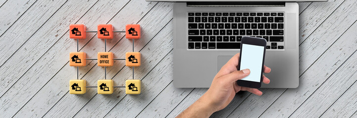cube grid with message HOME OFFICE and hand over a computer on wooden background
