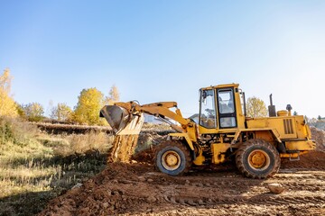 large yellow wheel loader aligns a piece of land for a new building. Preparation of the land for the auction. Leveling the landscape and adding sand for construction.