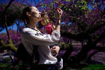young woman and her daughter in the park with flowers