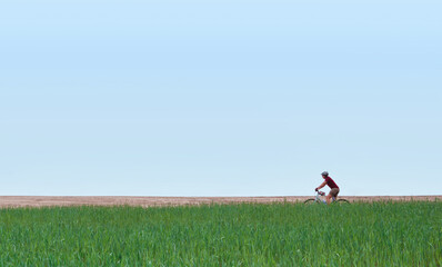 Girl on a bicycle in the field against the sky. Minimal concept.