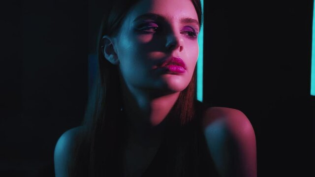 Neon model portrait. Female elegance. Woman with evening makeup posing in purple blue glow.