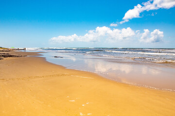 Reflexos do céu na areia molhada pelo mar na praia de Torres, RS, Brasil