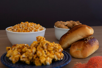 Close up of typical June Party foods on a wooden table: Popcorn, cornmeal cake, corn kernels, peanut pods and small country hats. Copy space. Selective focus.