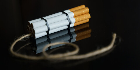 Cigarettes are twisted into a dynamite checker with a filament on a black reflective surface.