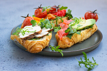 Variety of croissant sandwiches with grilled pepper, tomatoes, smoked salmon, turkey, avocado and...