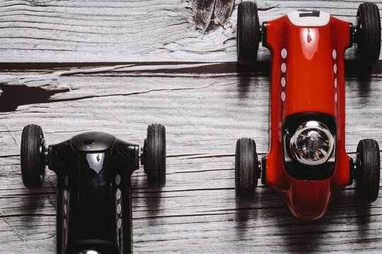 Fototapeta Two toy vintage racing cars red and black racing on a wooden surface
