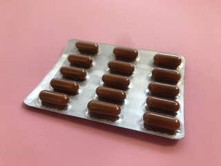 unused packaging with oval oblong red tablets. medicines for stomach pains. drugs on a pink glamorous paper background. medicines for viruses