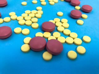 round pink and yellow pills volumetric structure on a blue matte background. health medications. Herbal medicines poured from the packaging. medical background