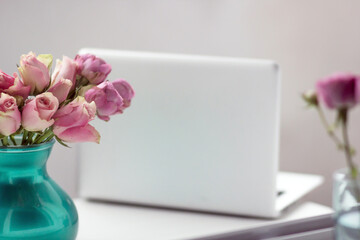 Vase of flowers and an open laptop in the background