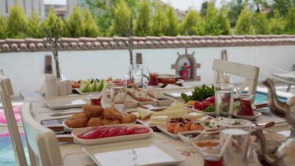 Concept promotional morning breakfast in the hotel, tasty Egg Benedict,Turkish and French Breakfast, tea and orange juice. near swimming pool	