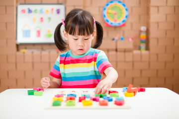 Fototapeta premium toddler girl learning letter blocks for homeschooling