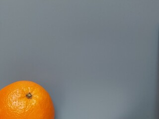 Beautiful bright orange orange with shiny thick peel on a gray background. Fruit bottom left. Free...