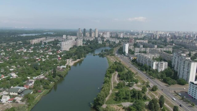 View to big city from sky. Tiny townhouses and modern skyscrapers divided by the lake. Aerial drone footage.