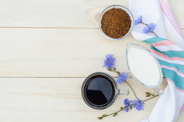 medical healthy diet drink from chicory root with milk or cream on wooden background, copy space, place for text. natural coffee substitute, blue flowers of Cichorium intybus. drink for children.