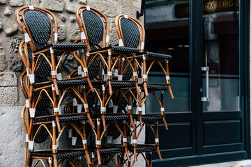 Chaises fauteuils d'une terrasse de bistro parisien rangés empilés dans la rue