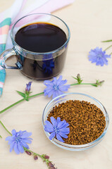Obraz na płótnie Canvas instant freeze dried granules from chicory root on a wooden background. dry powder and fresh blue flowers. natural coffee substitute. drink for children. vertical