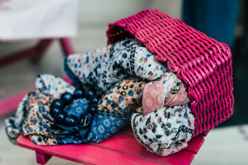 Foulard en tissu coloré à motif fleuri rangés dans un panier en osier rose