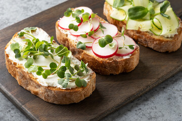 Tree sandwiches with fresh radish microgreens and cream cheese on grey background. Close up.
