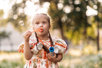 A girl with Down syndrome blows bubbles. The daily life of a child with disabilities. Chromosomal...