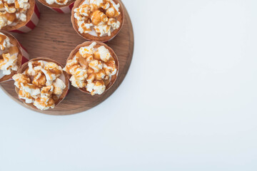 A flat lay style image with salted caramel popcorn vanilla frosted cupcakes arranged in a circular fashion in the top left corner of the image.  Plain white background with copy text space