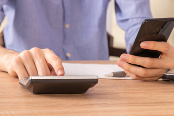 hands with calculator and mobile phone in the foreground