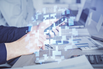 Double exposure of man's hand holding and using a digital device and data theme hologram drawing. Technology concept.