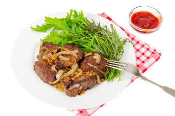 Pieces of fried liver with onions, fresh leaves of salads