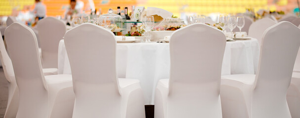 Served a full meal table with chairs in white covers ready to be received 