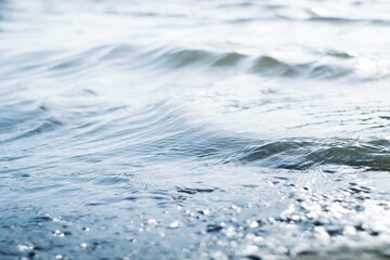 Beautiful summer natural background. Blue waves and sun glare on the water