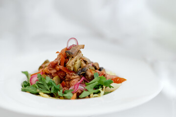 Eggplant onion vegetable salad on a white plate on a white background 