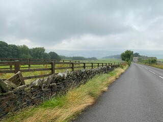 Country road, with dry stone walls, heavy rain clouds, and mist near, Slaithwaite, Huddersfield, UK
