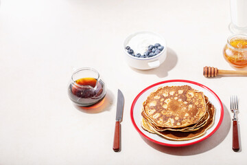 A stack of plain pancakes served with honey and blueberry