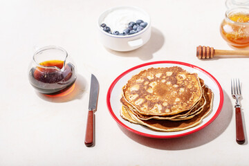 A stack of plain pancakes served with honey and blueberry
