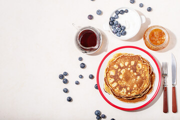 A stack of plain pancakes served with honey and blueberry