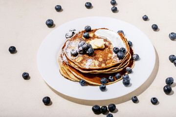 A stack of plain pancakes served with honey and blueberry