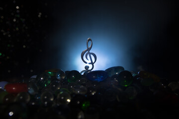 Musical symbol treble clef stainless steel miniature with colorful toned light on foggy background....