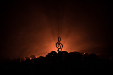 Musical symbol treble clef stainless steel miniature with colorful toned light on foggy background. Selective focus