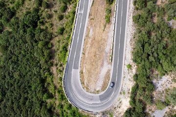 Aerial view of winding road in high mountain pass trough green pine woods. High quality photo