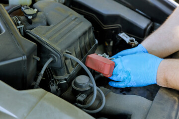 Hands of car mechanic working in auto repair service replacement battery