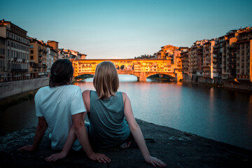Fototapeta na wymiar Photo of a couple on a bridge of the Arno river in italy at sunset