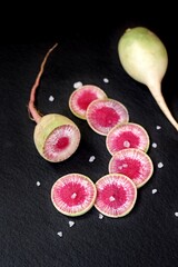 watermelon radish in a cut on a black background slate. delicious winter root vegetable.