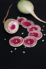 watermelon radish in a cut on a black background slate. delicious winter root vegetable.