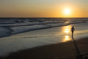 Person walking on the beach at sunset