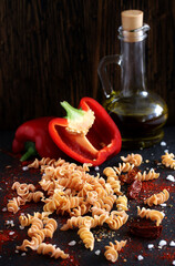 raw fusilli paprika pasta, close-up on a black background. homemade pasta without dyes from durum...