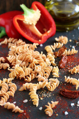 raw fusilli paprika pasta, close-up on a black background. homemade pasta without dyes from durum...